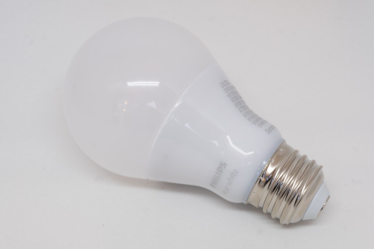 A physical Philips Hue white bulb on a white surface.